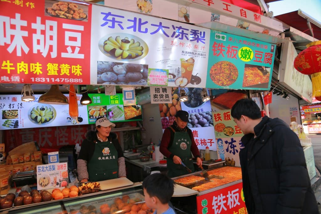Vibrant Chinese street food market with various snacks and grilled dishes